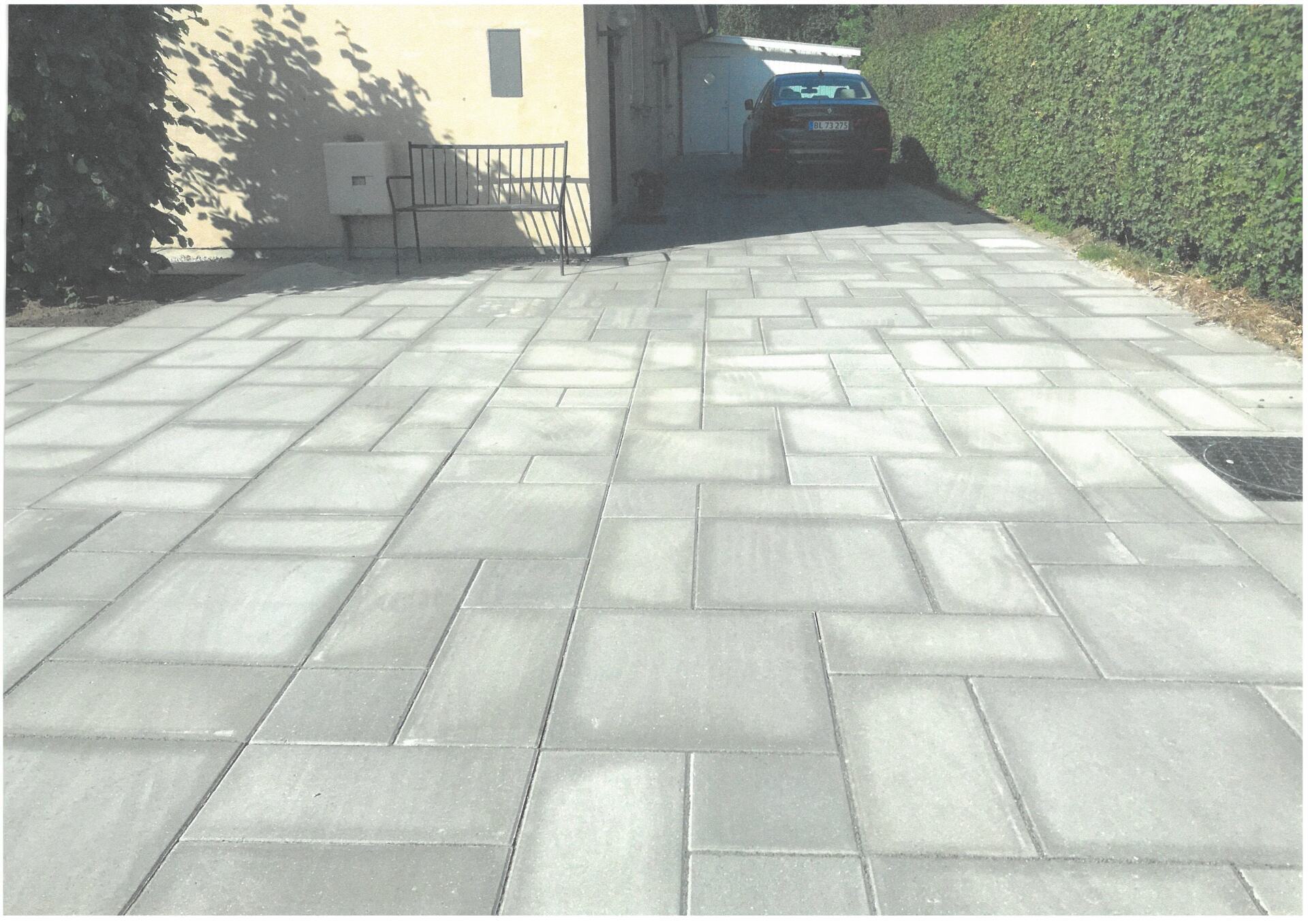 Stor stenbelagt indkørsel ved siden af et hjem