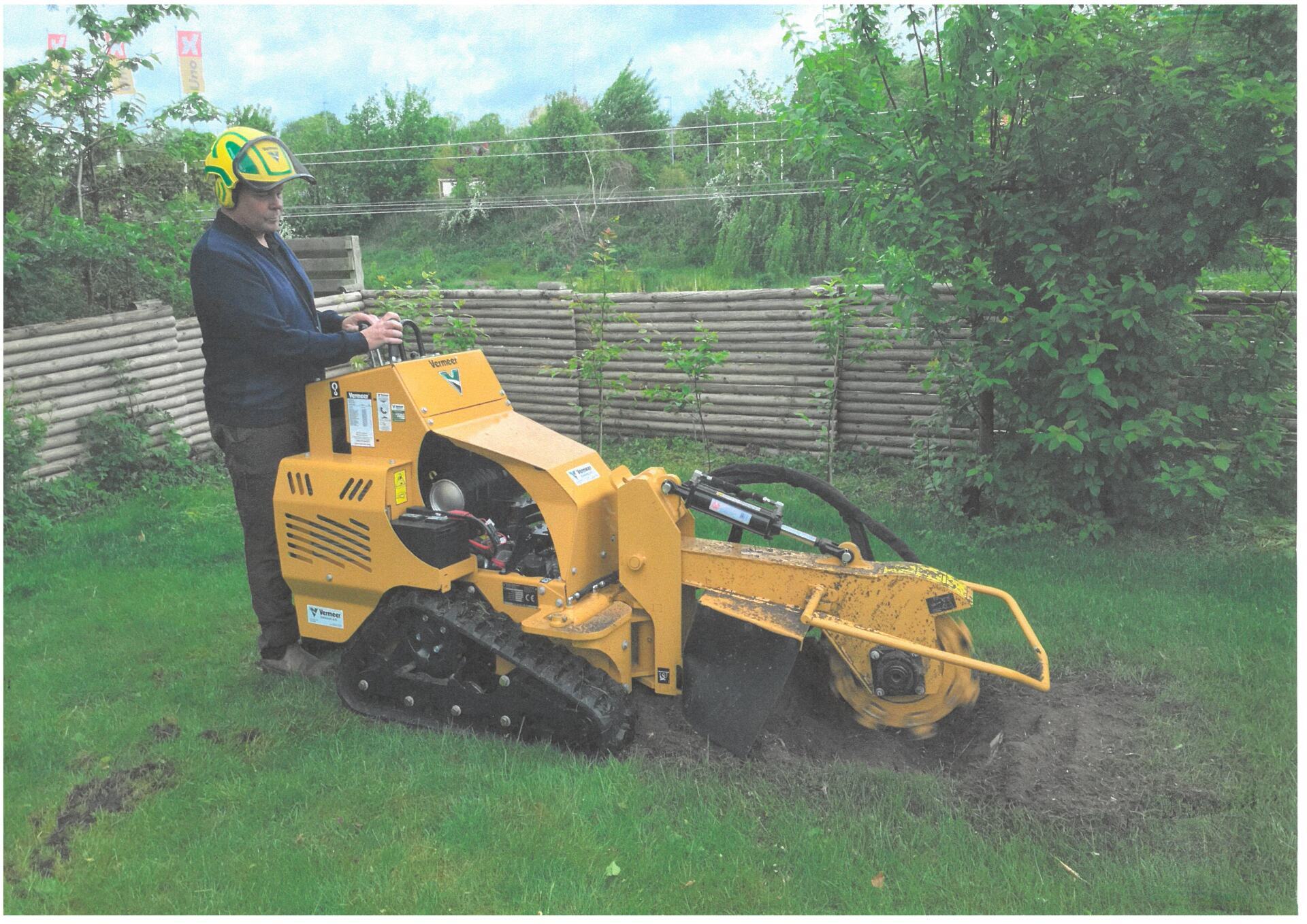 Mand bruger stor maskine til at grave en træstub op