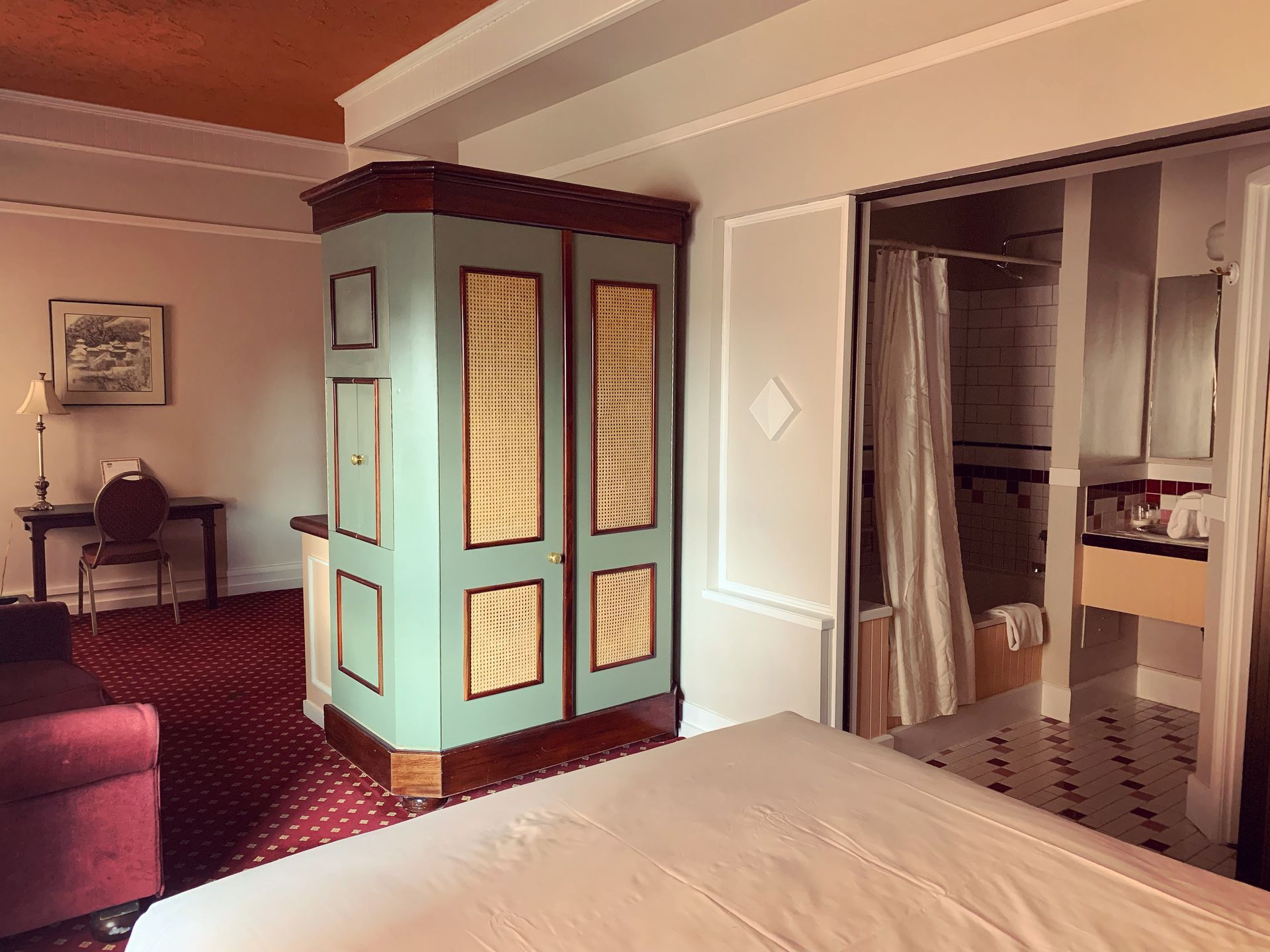 A hotel room with a bed , chair , desk , and wardrobe.
