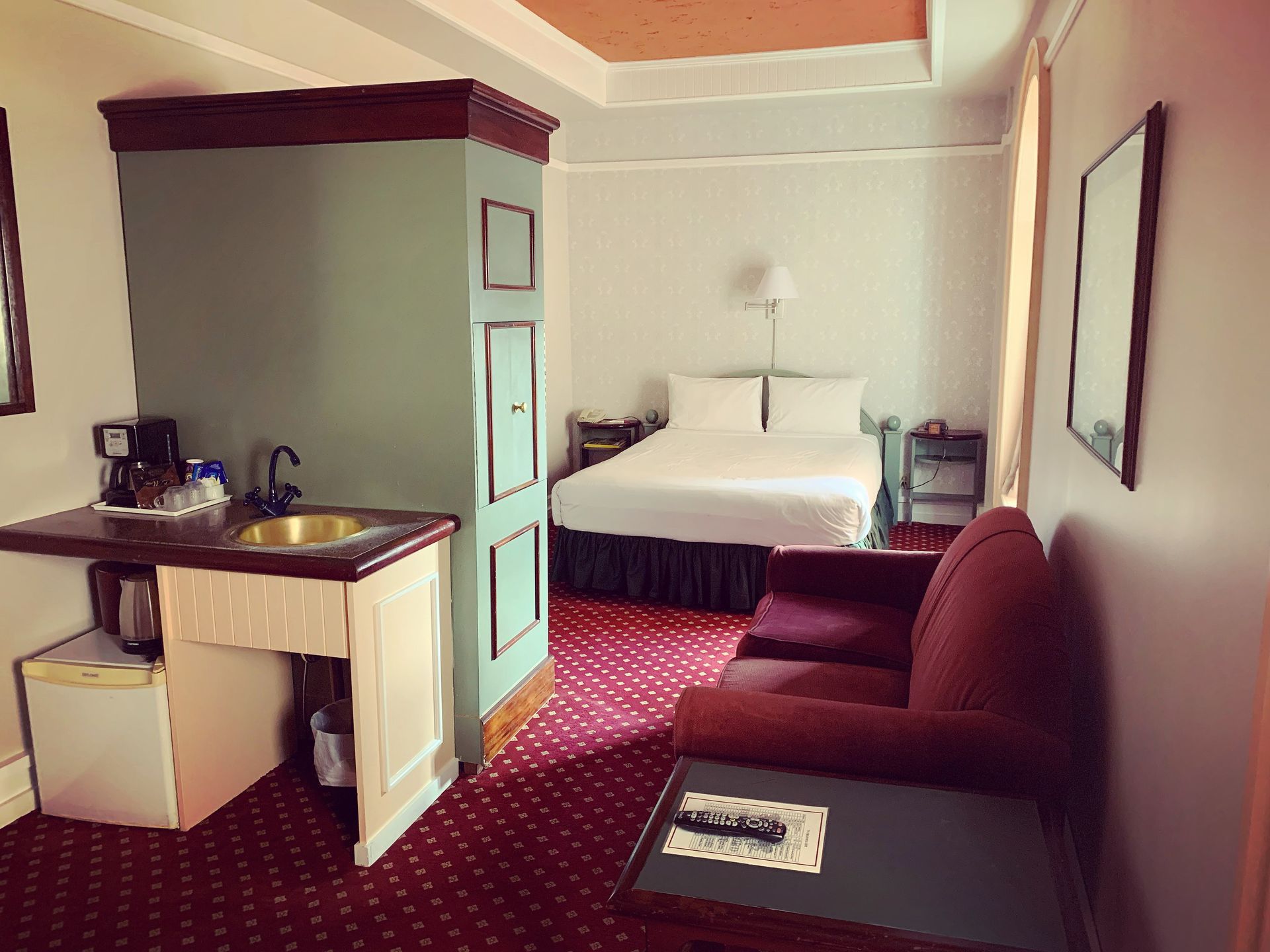 A hotel room with a bed , couch , table and sink.