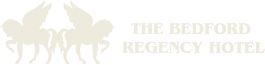 A white logo for the bedford regency hotel
