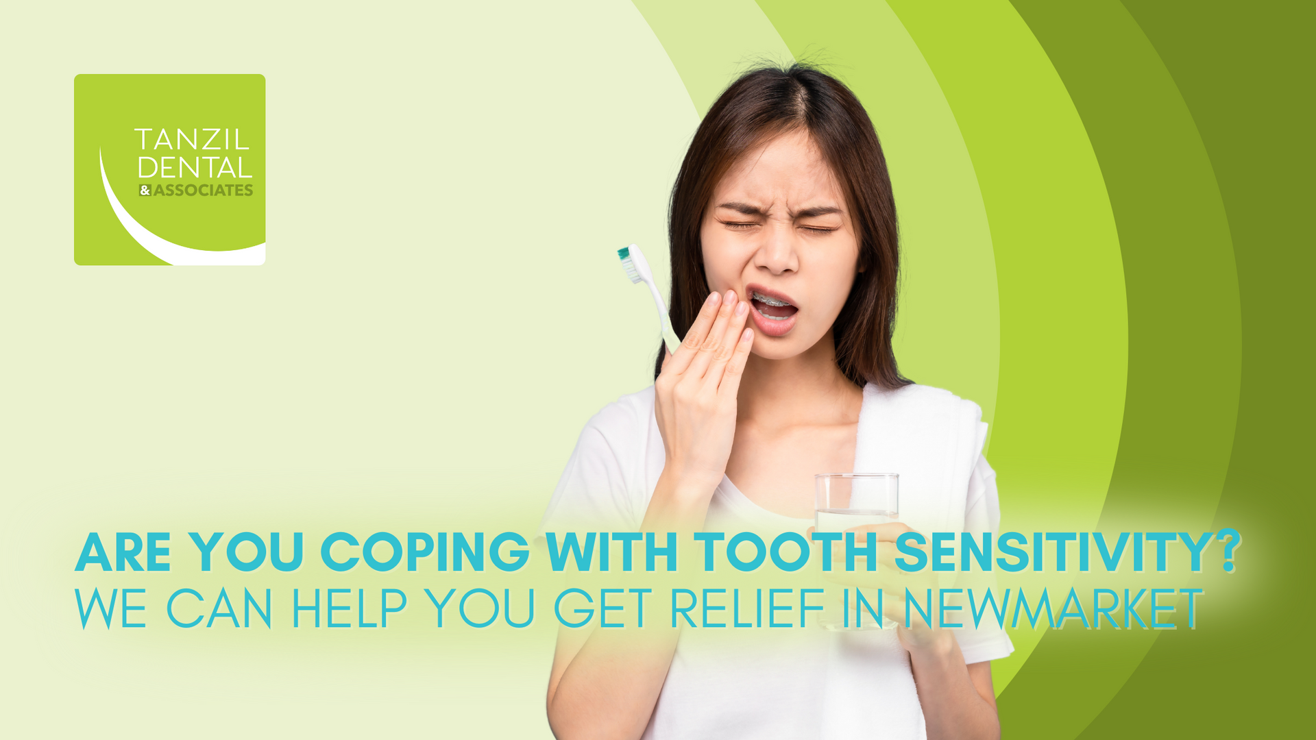 A woman is holding her mouth in pain while brushing her teeth.