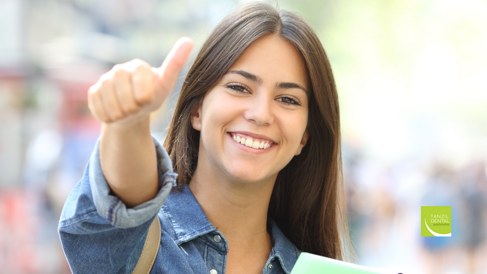 A woman is smiling and giving a thumbs up while holding a book.