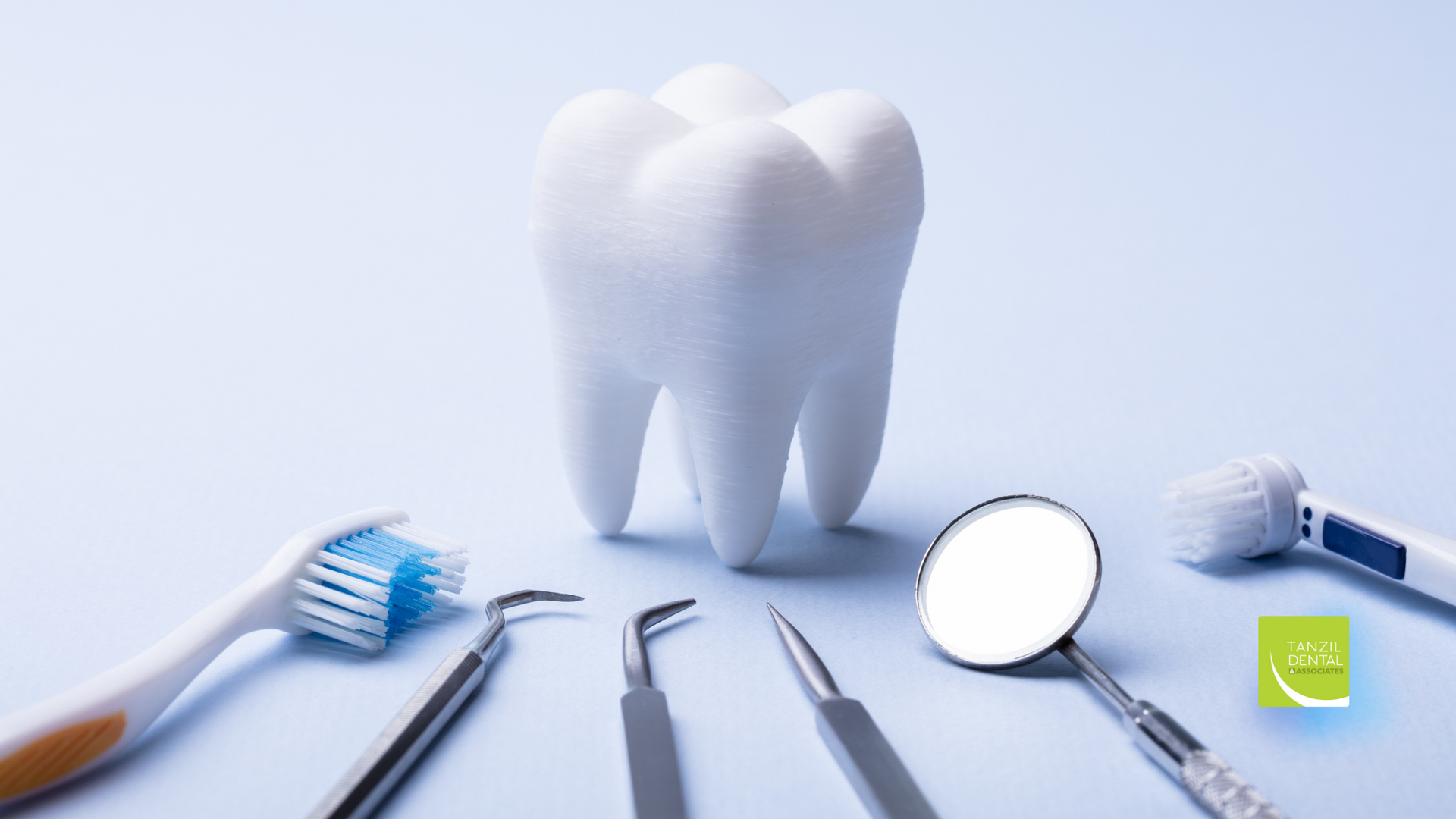A tooth is surrounded by dental instruments on a blue surface.