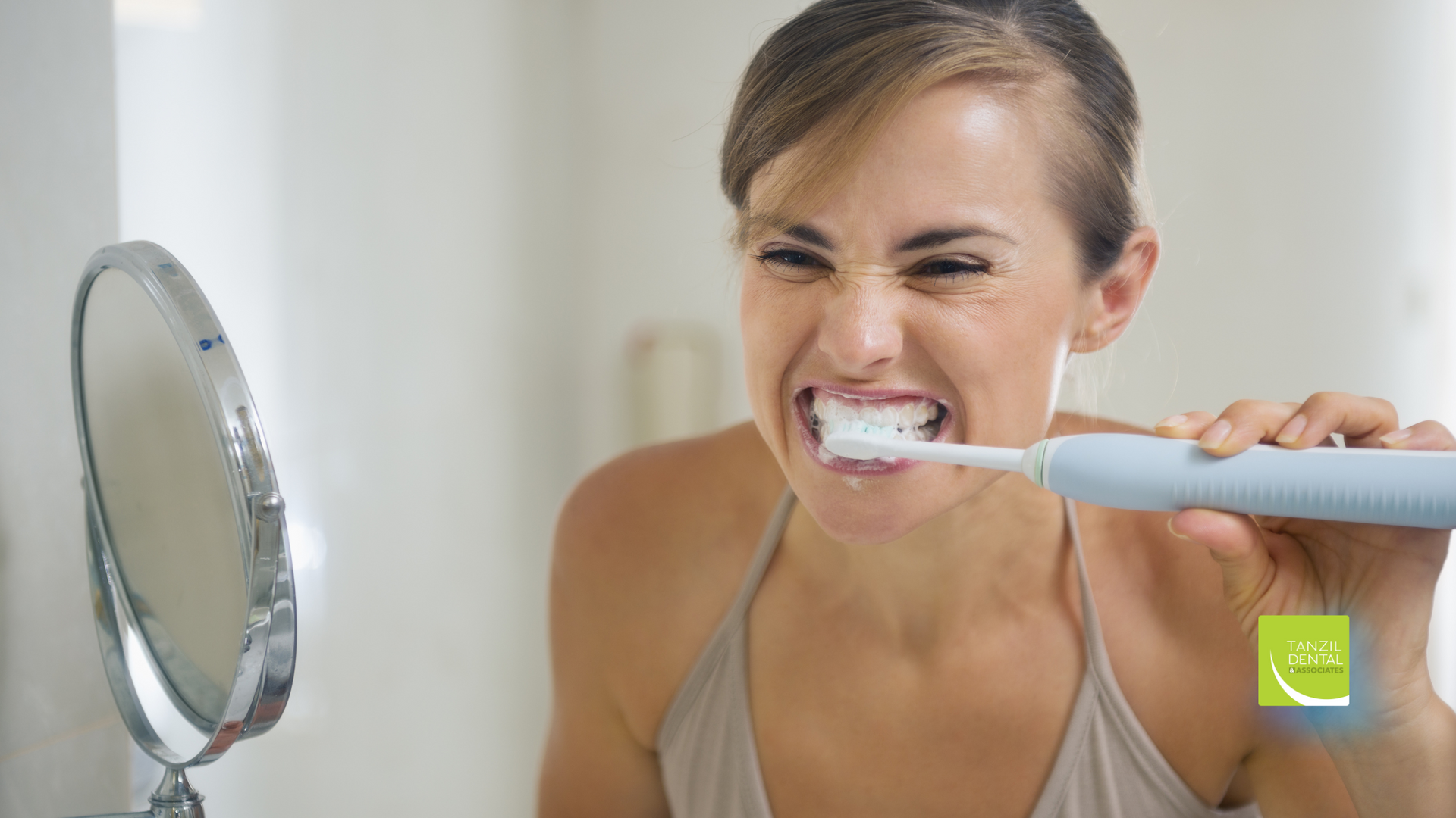 A woman is brushing her teeth in front of a mirror.