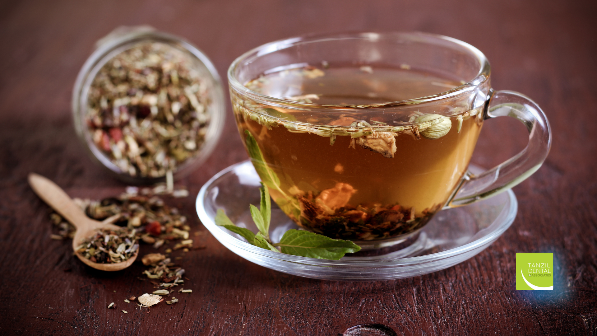 A cup of tea is sitting on a saucer on a wooden table.