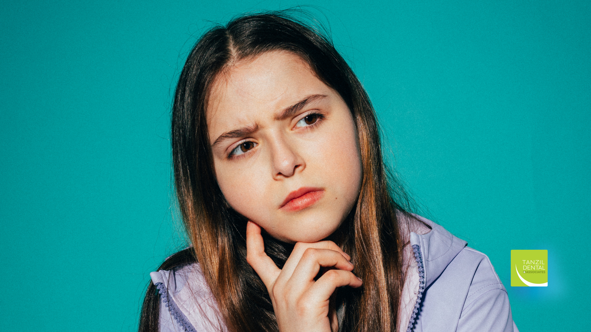 A young woman is thinking with her hand on her chin.