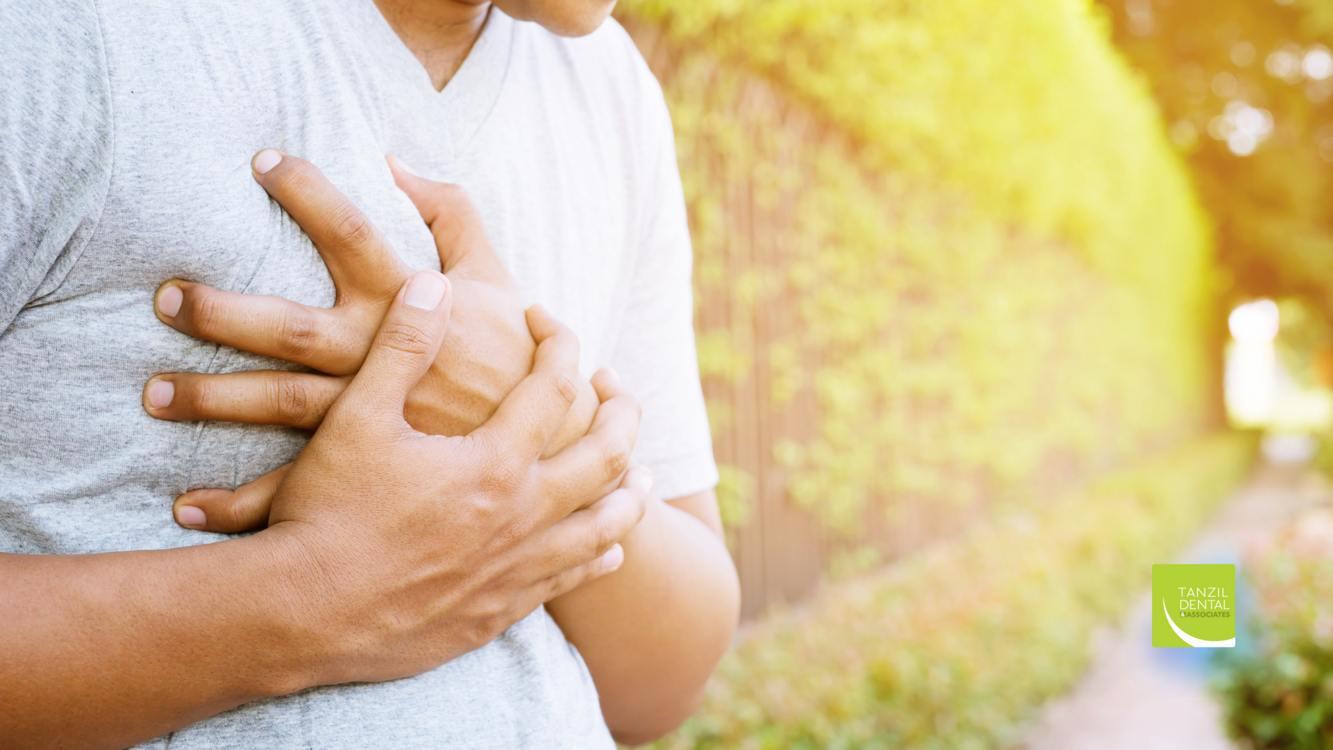 A man is holding his chest because he has a heart attack.