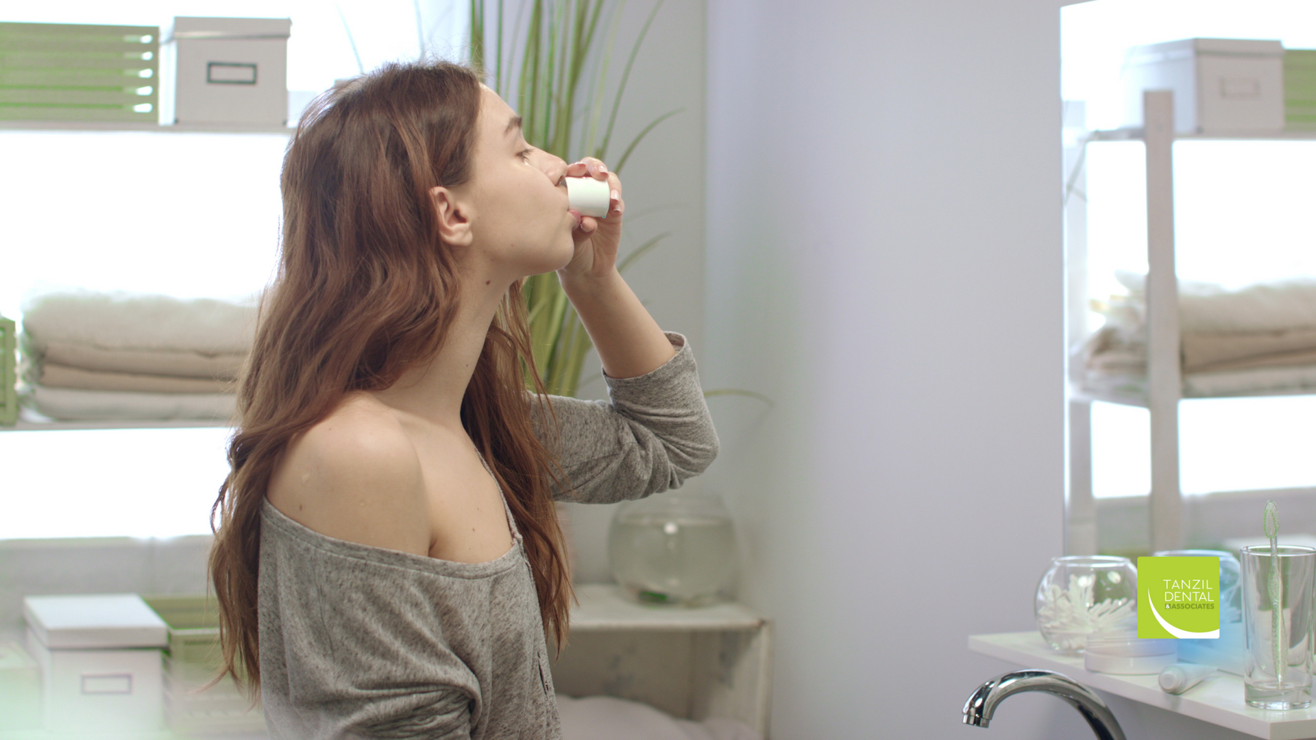 A woman is brushing her teeth in a bathroom.