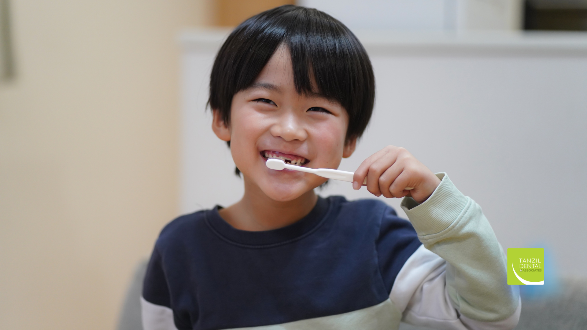 Smiling child brushing teeth indoors.