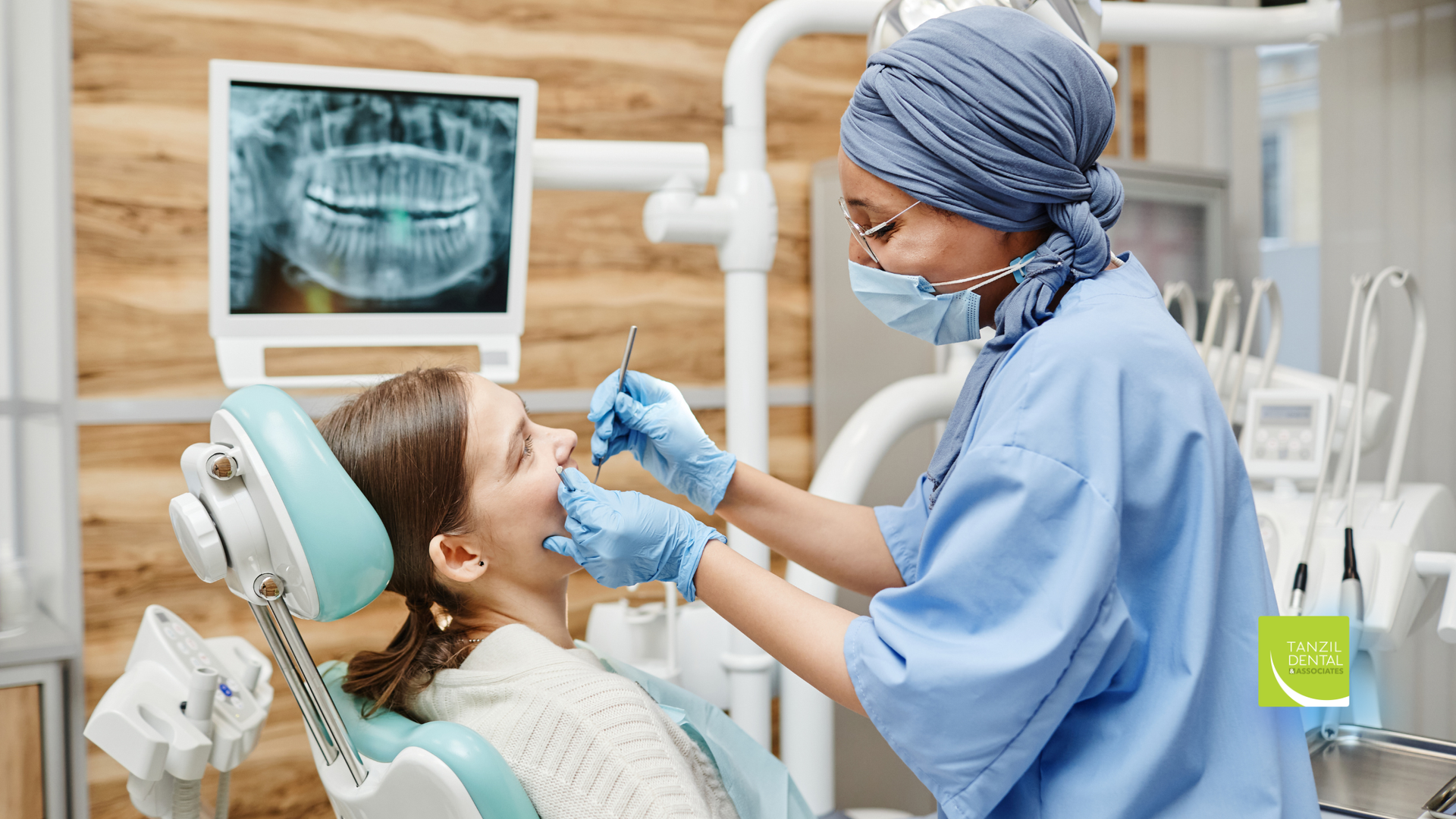 Dentist examining patient's teeth. Dental office. X-ray screen visible. Both are wearing masks.