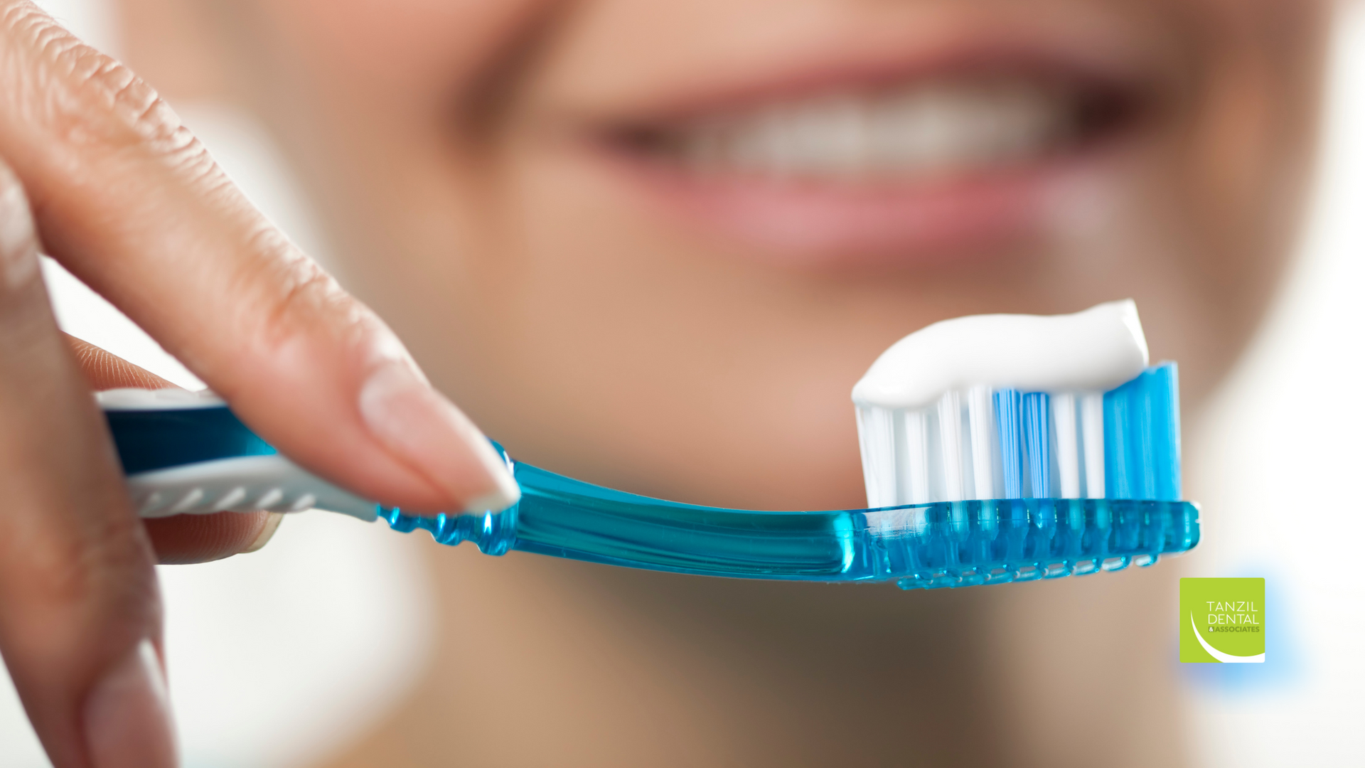 A woman is brushing her teeth with a blue toothbrush.