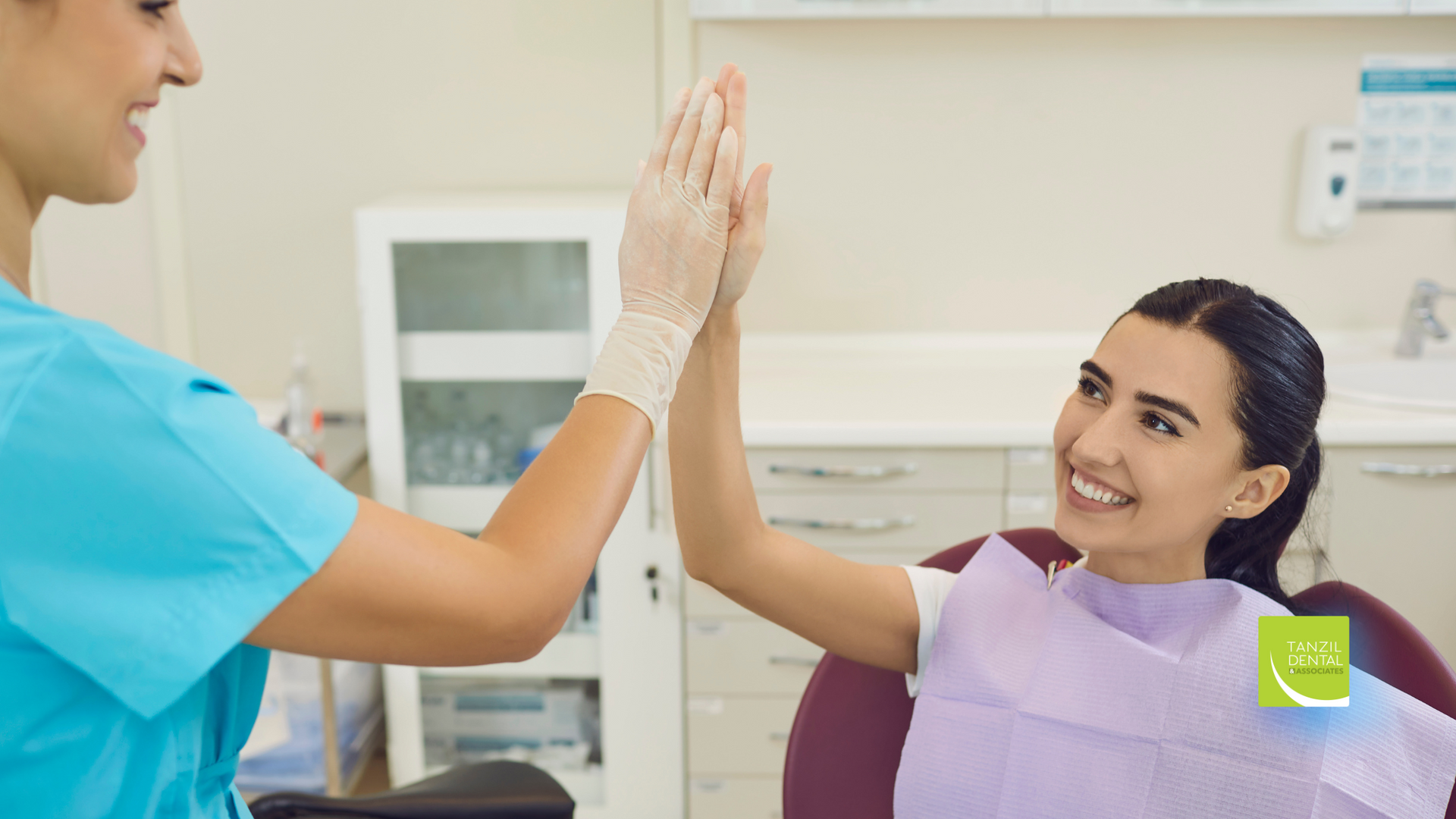 A dentist and a patient are giving each other a high five in a dental office.