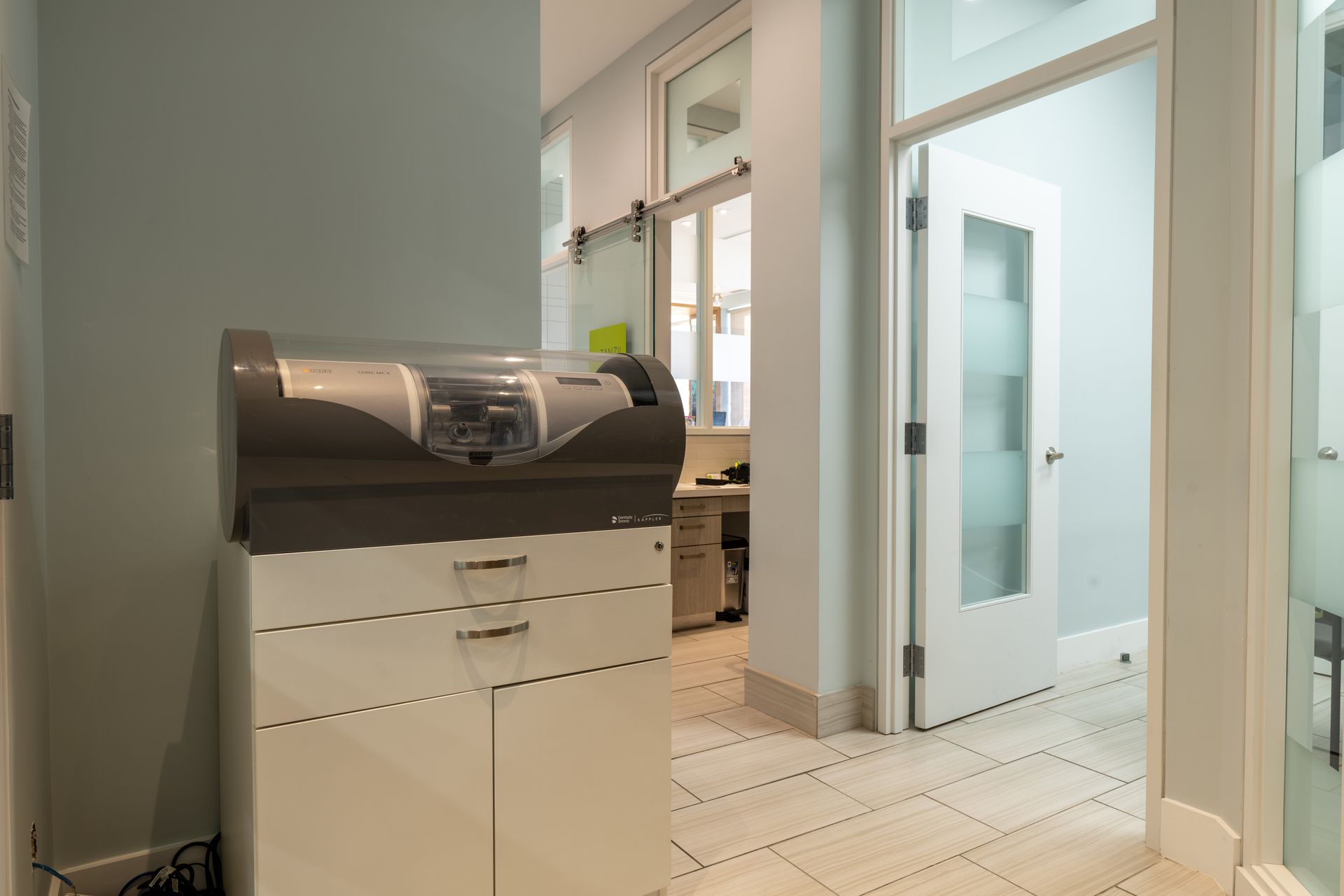 A machine is sitting on top of a white cabinet in a hallway.
