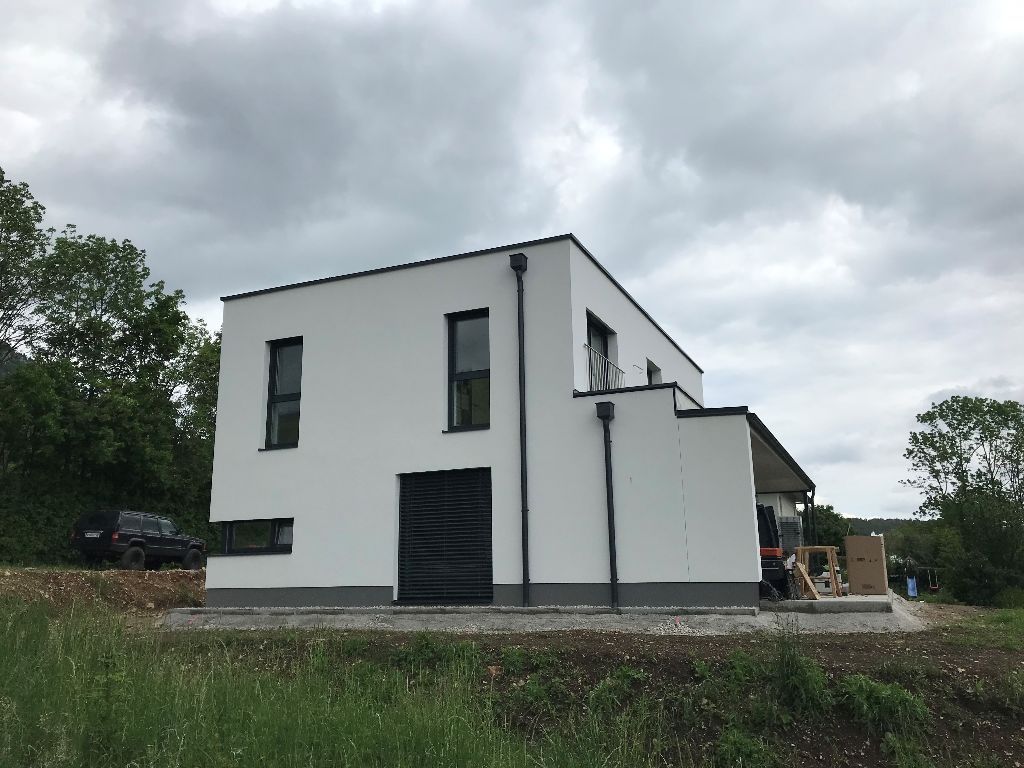 ein weißes Haus mit einem schwarzen Auto davor