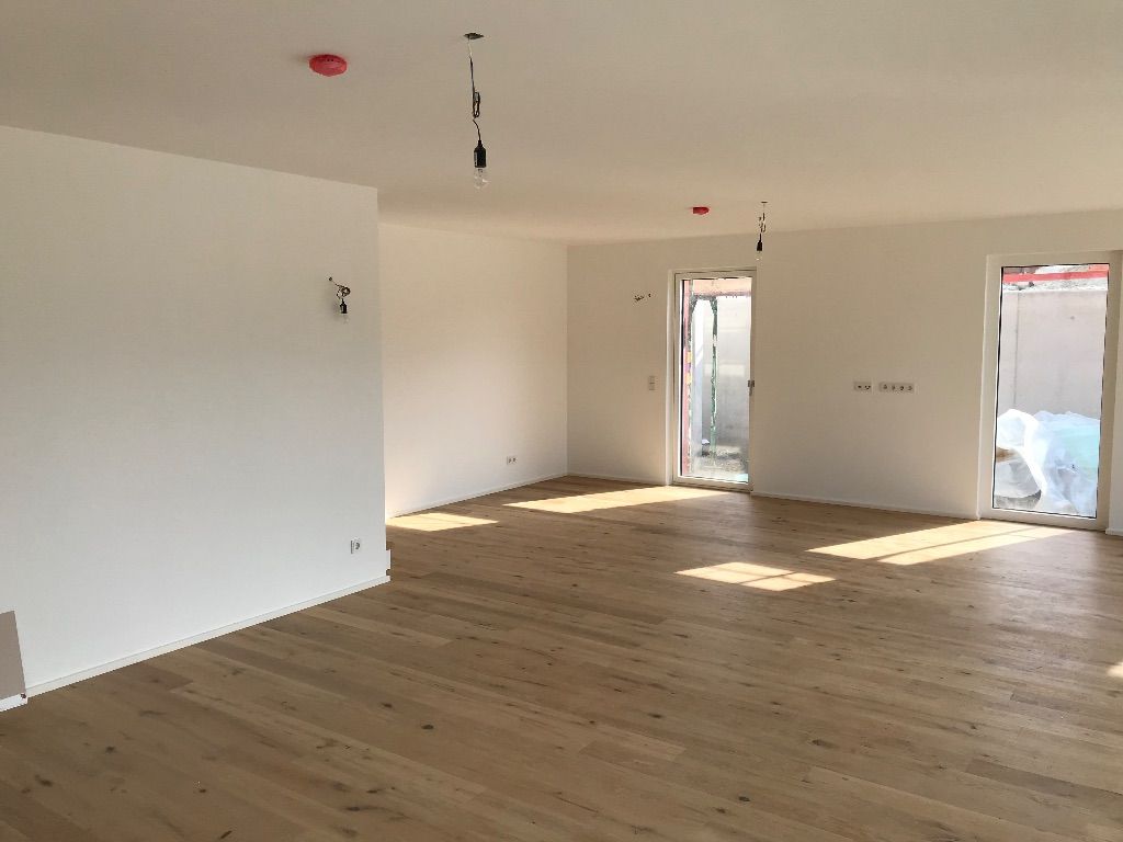 ein leerer Raum mit Holzboden und weißen Wänden