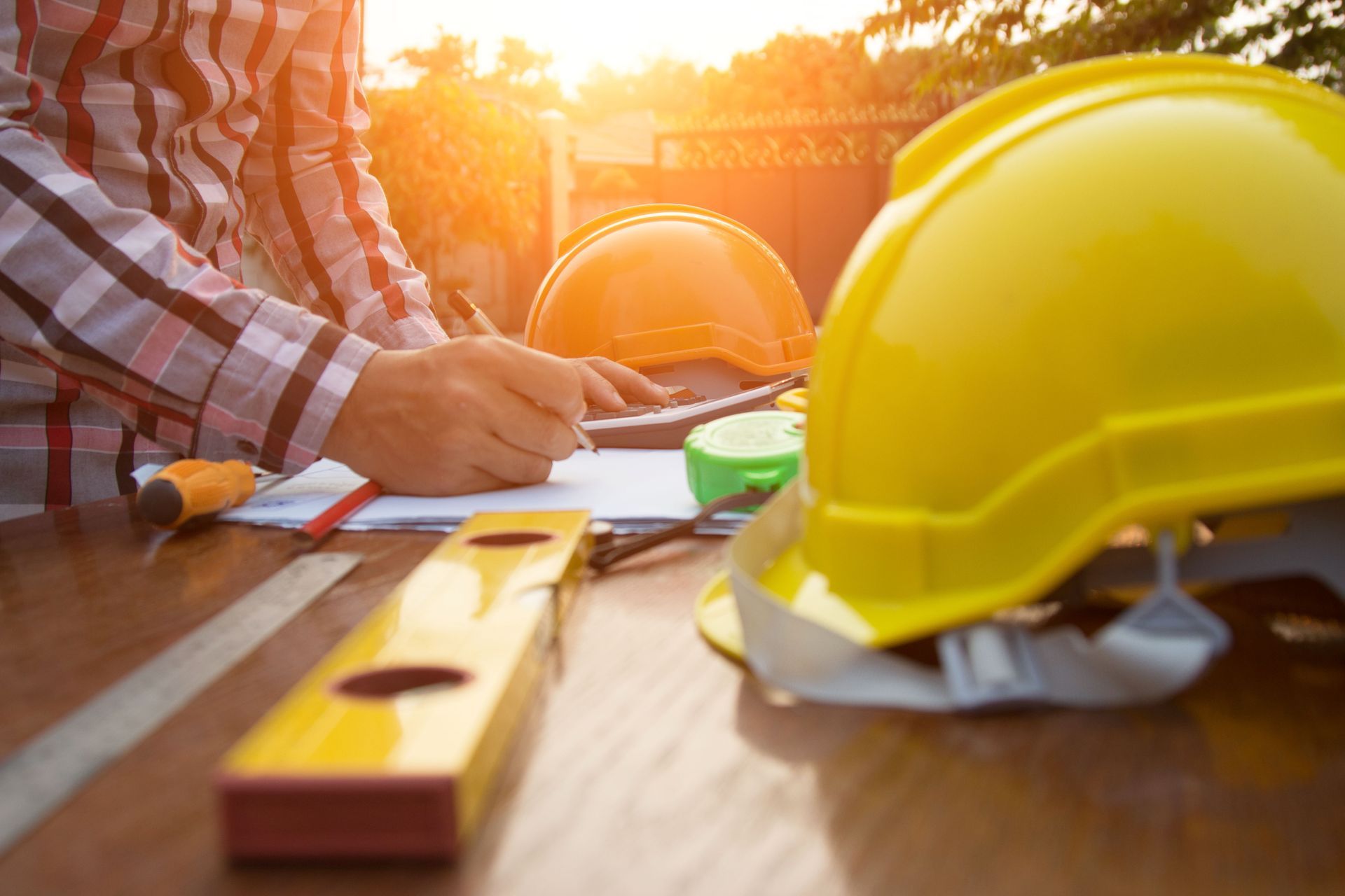 ein Mann schreibt auf einem Blatt Papier neben einem gelben Helm