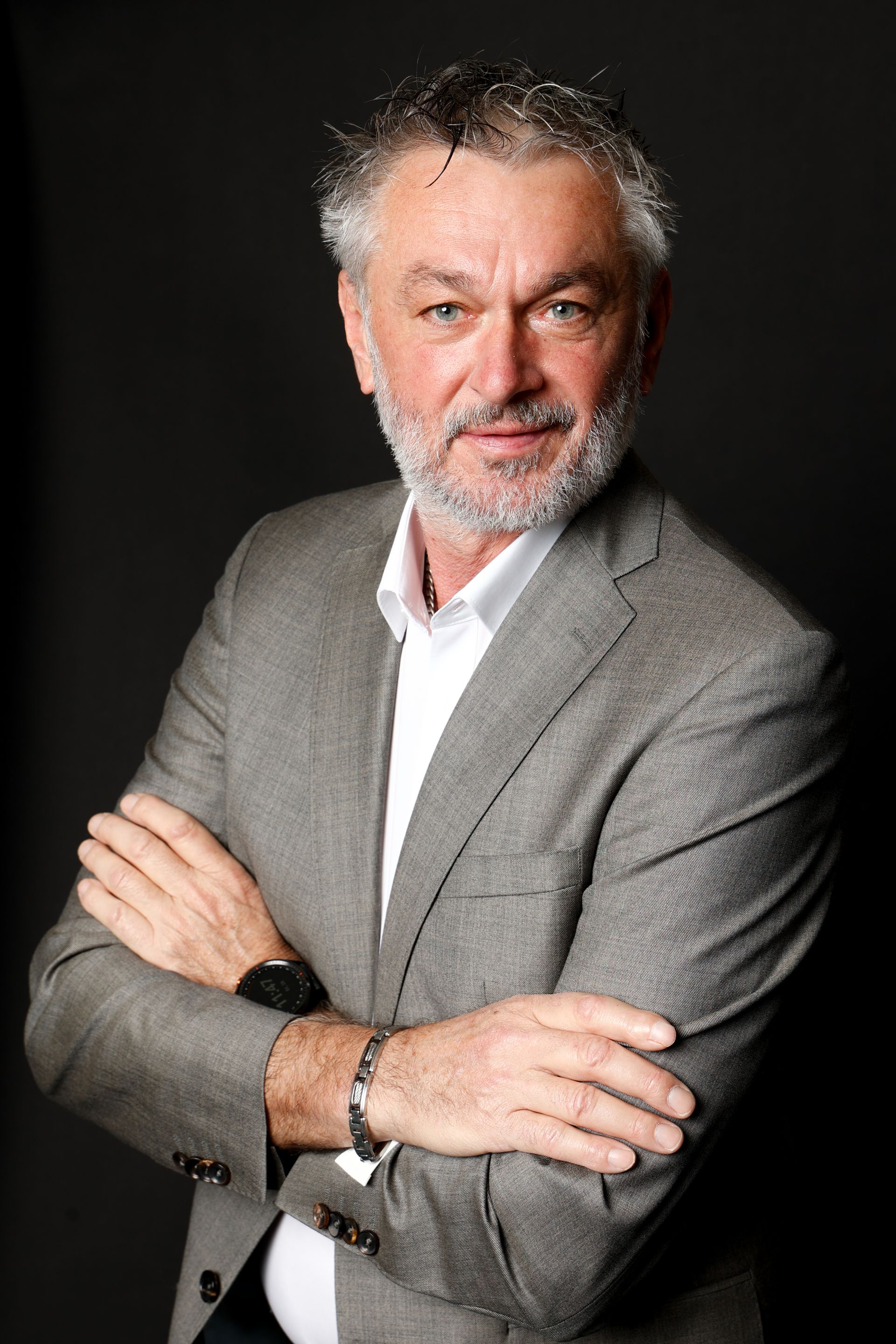 ein Mann mit Bart trägt einen grauen Anzug und weißes Hemd