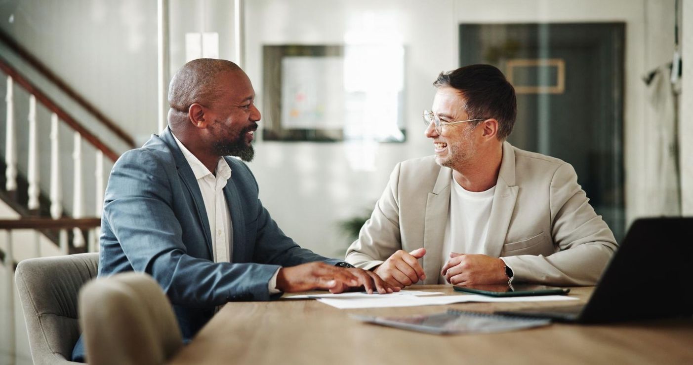 A couple consulting with a smiling lawyer in a wood-paneled office; the lawyer gestures.