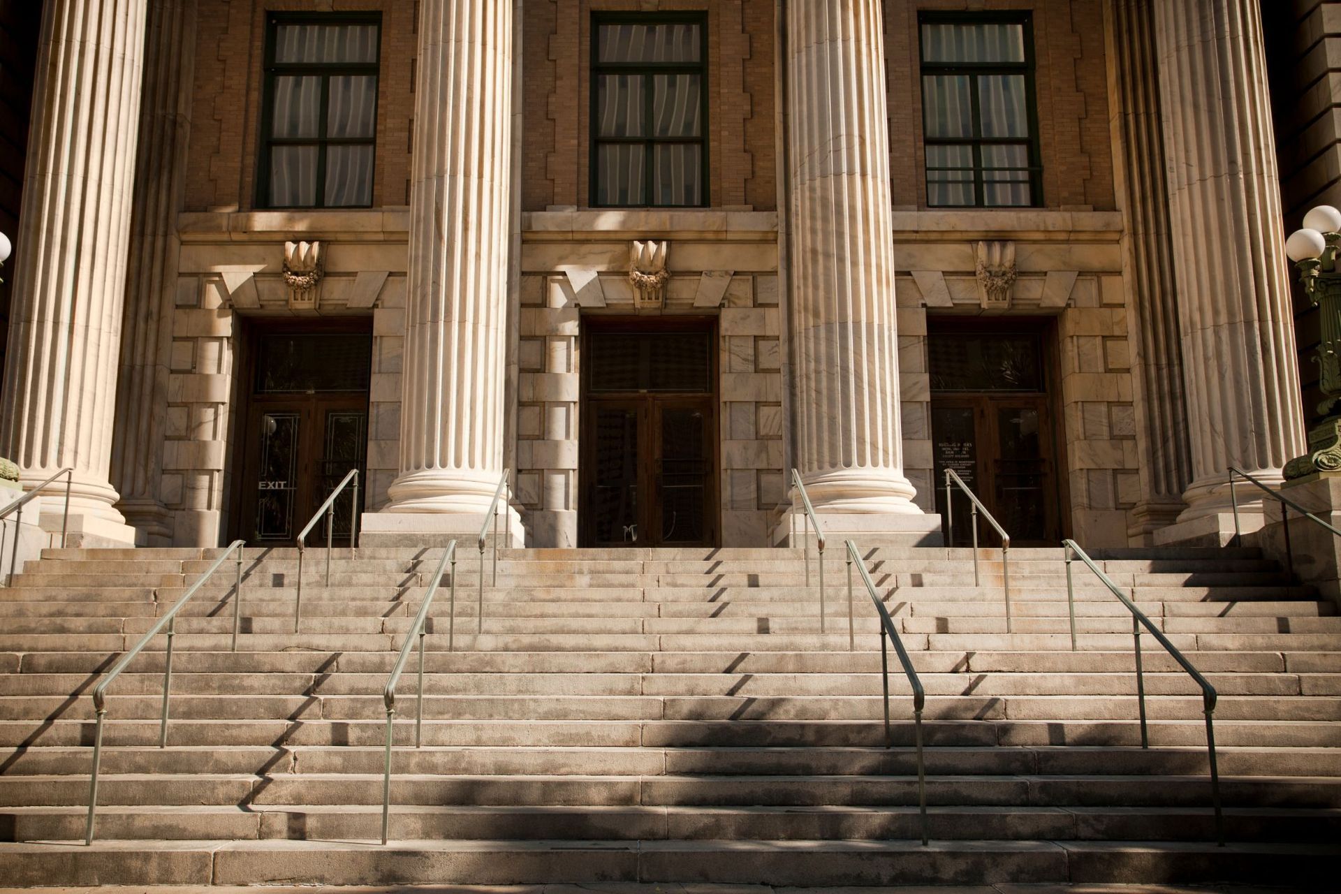 A man is carrying a little girl on his shoulders in a park.
