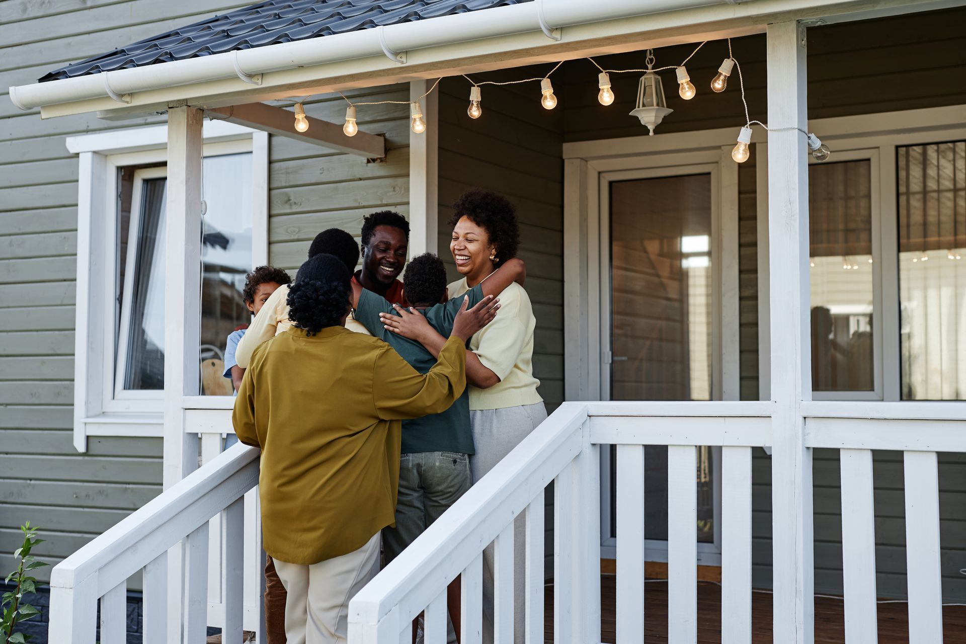 Group of people hugging on a porch with string lights.