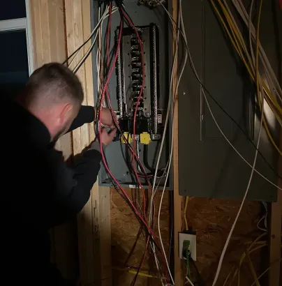 Electrician performing home wiring and electrical installation on residential breaker panel
