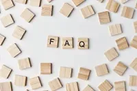 Wooden letter tiles spelling FAQ, surrounded by scattered blank tiles on a white background