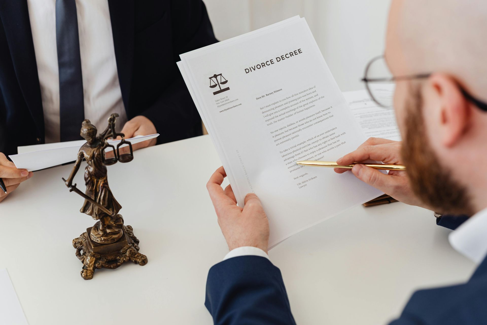 Two people reviewing a contract at a desk with a bronze scales of justice statue