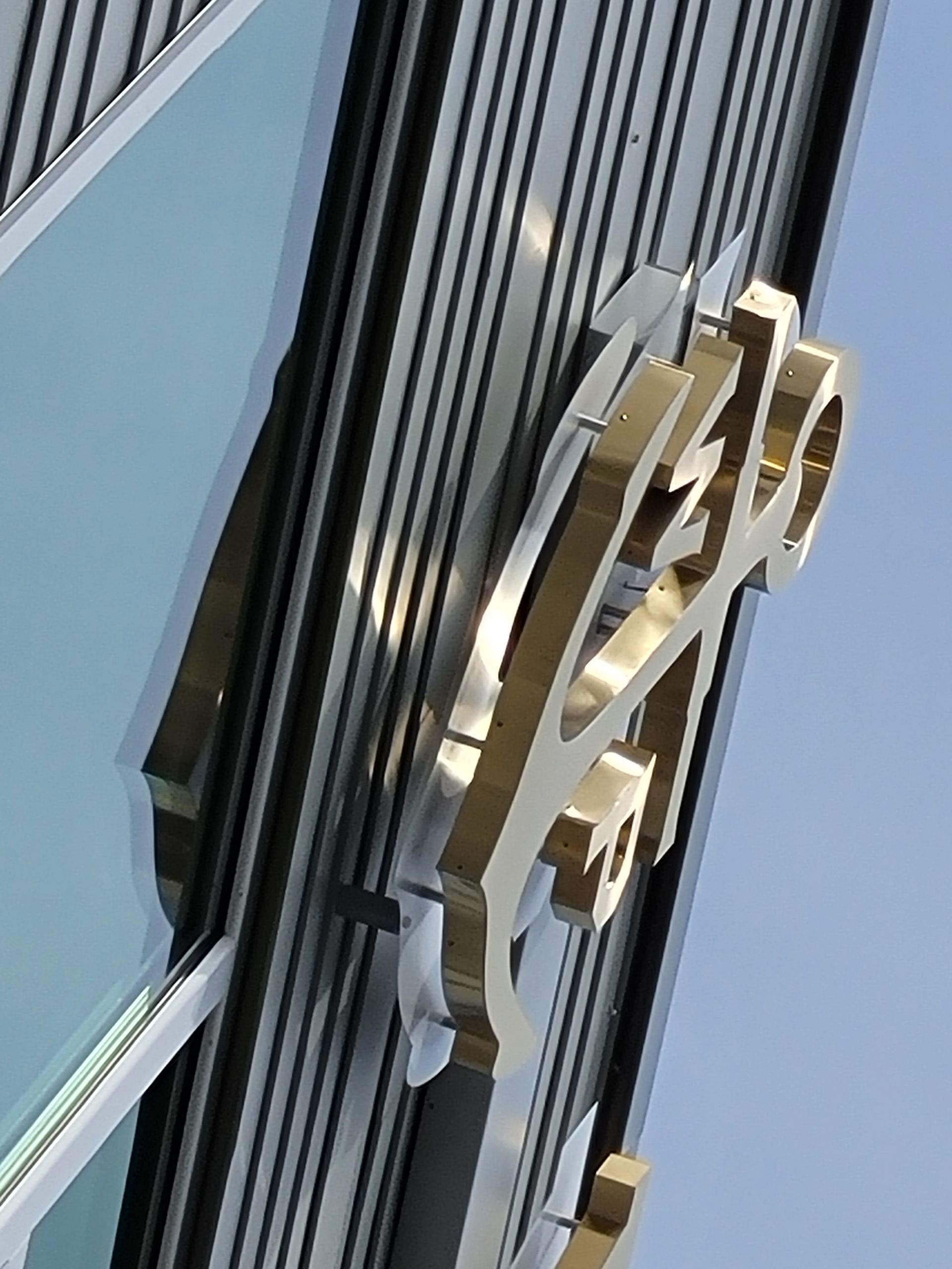 Gold and silver emblem on a building facade with a blue sky background