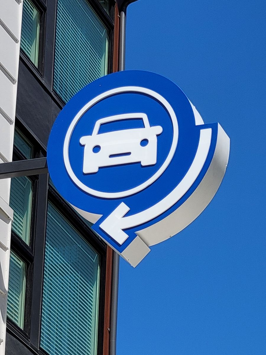 Blue and white car rental sign with a white car in a circle and a circling arrow