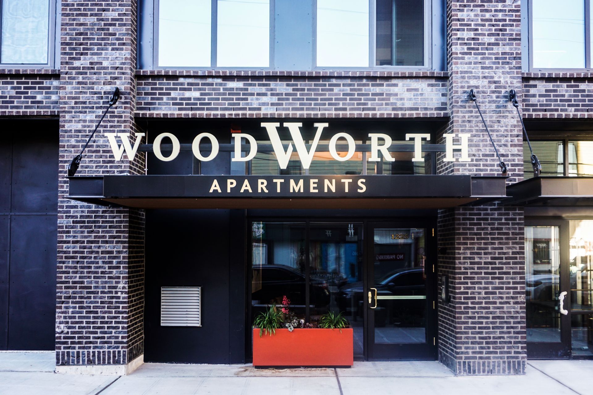 Woodworth apartments entrance with brick facade, awning, and signage