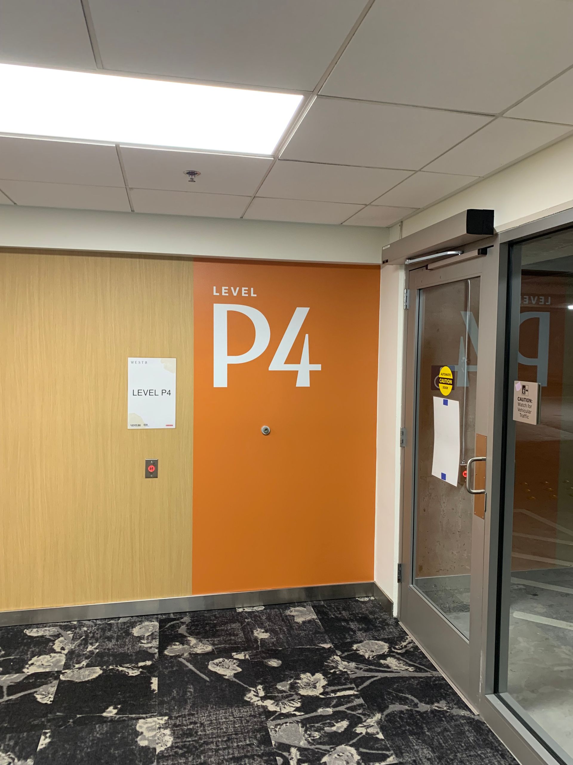 Level p4 entrance sign in orange and cream colors next to a glass door
