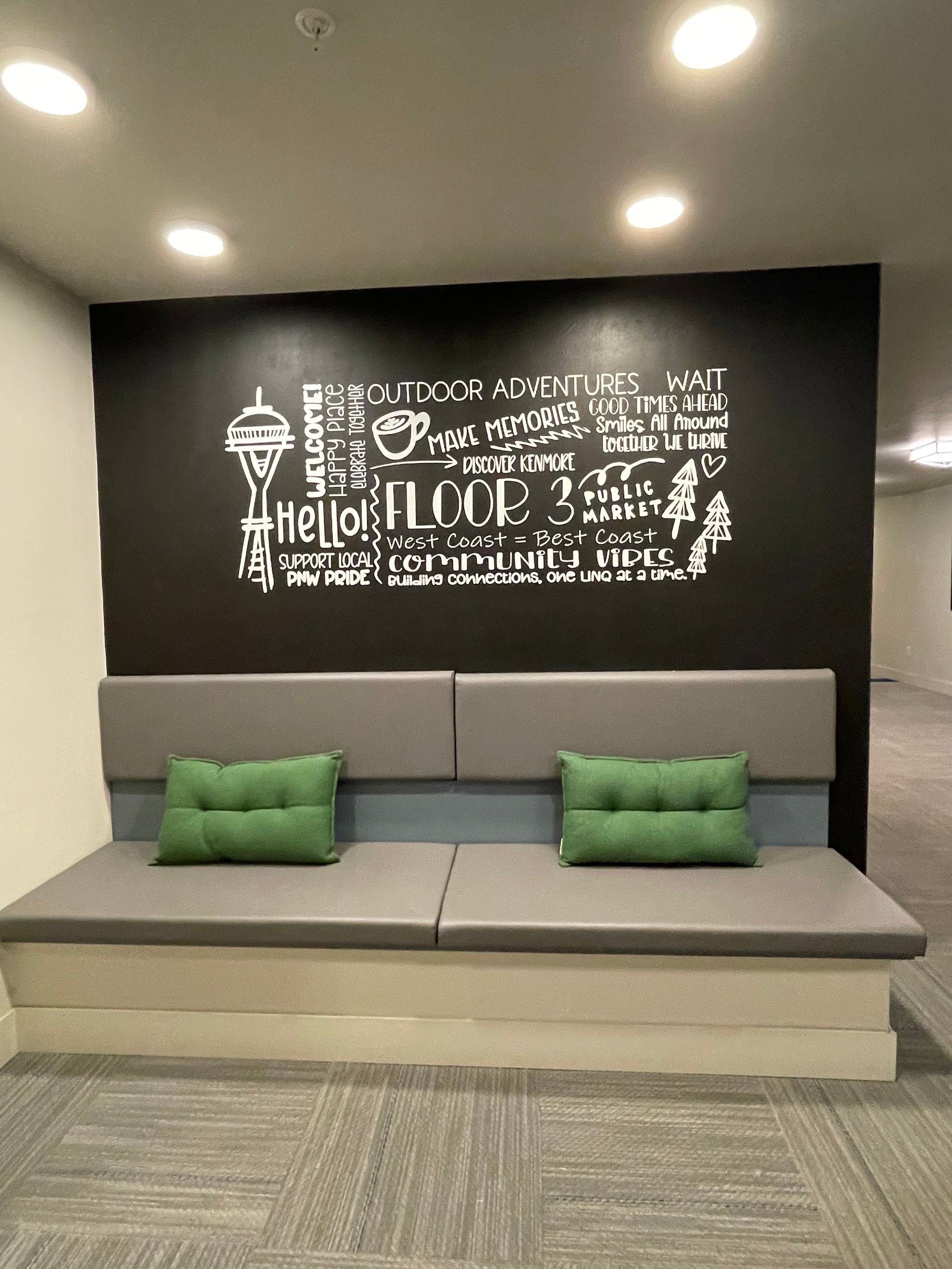 Gray bench with green pillows against a black wall with white text and a local landmark