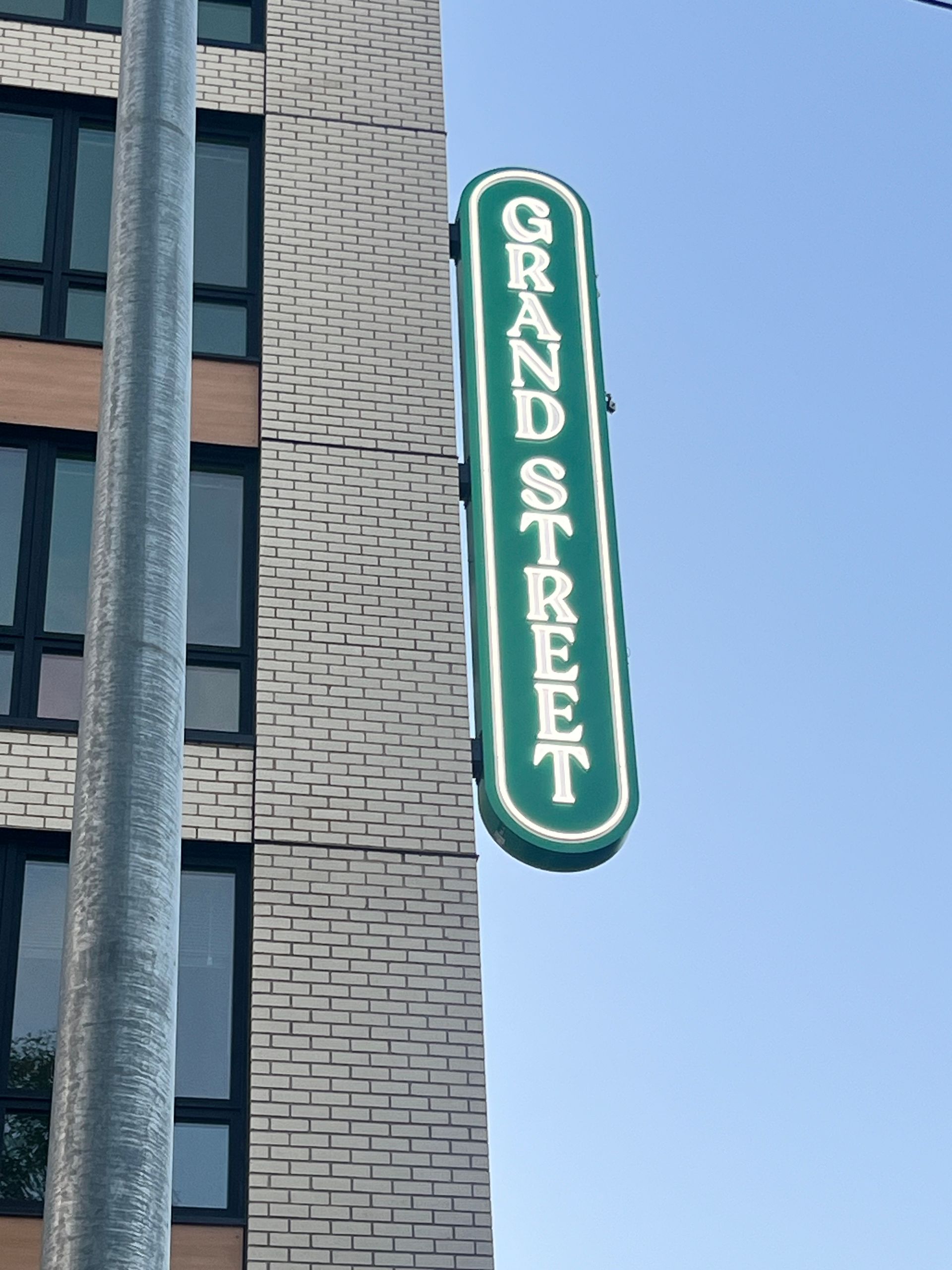 Green sign on brick building, against blue sky