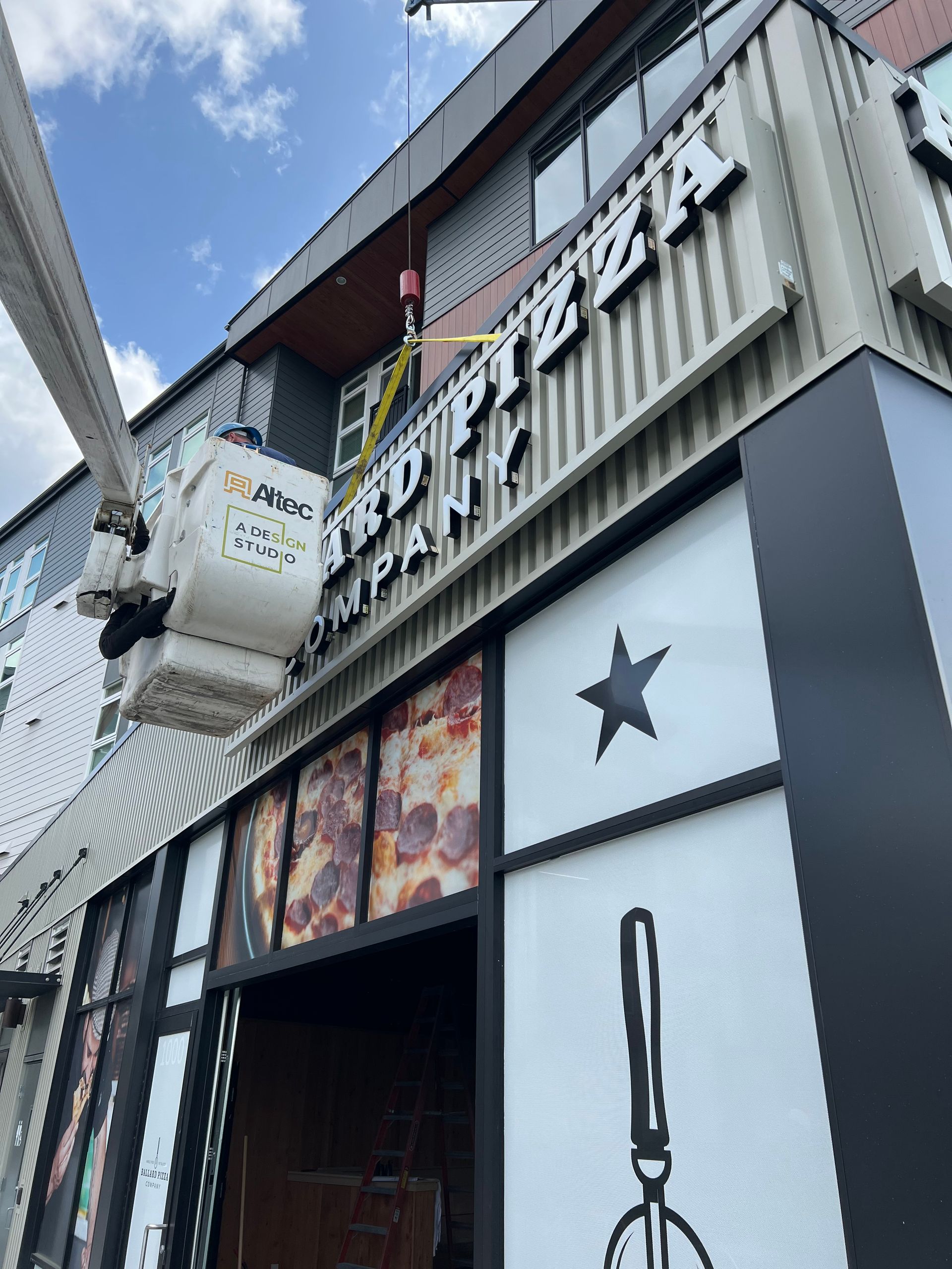 Signage being repaired on the exterior of a pizza restaurant