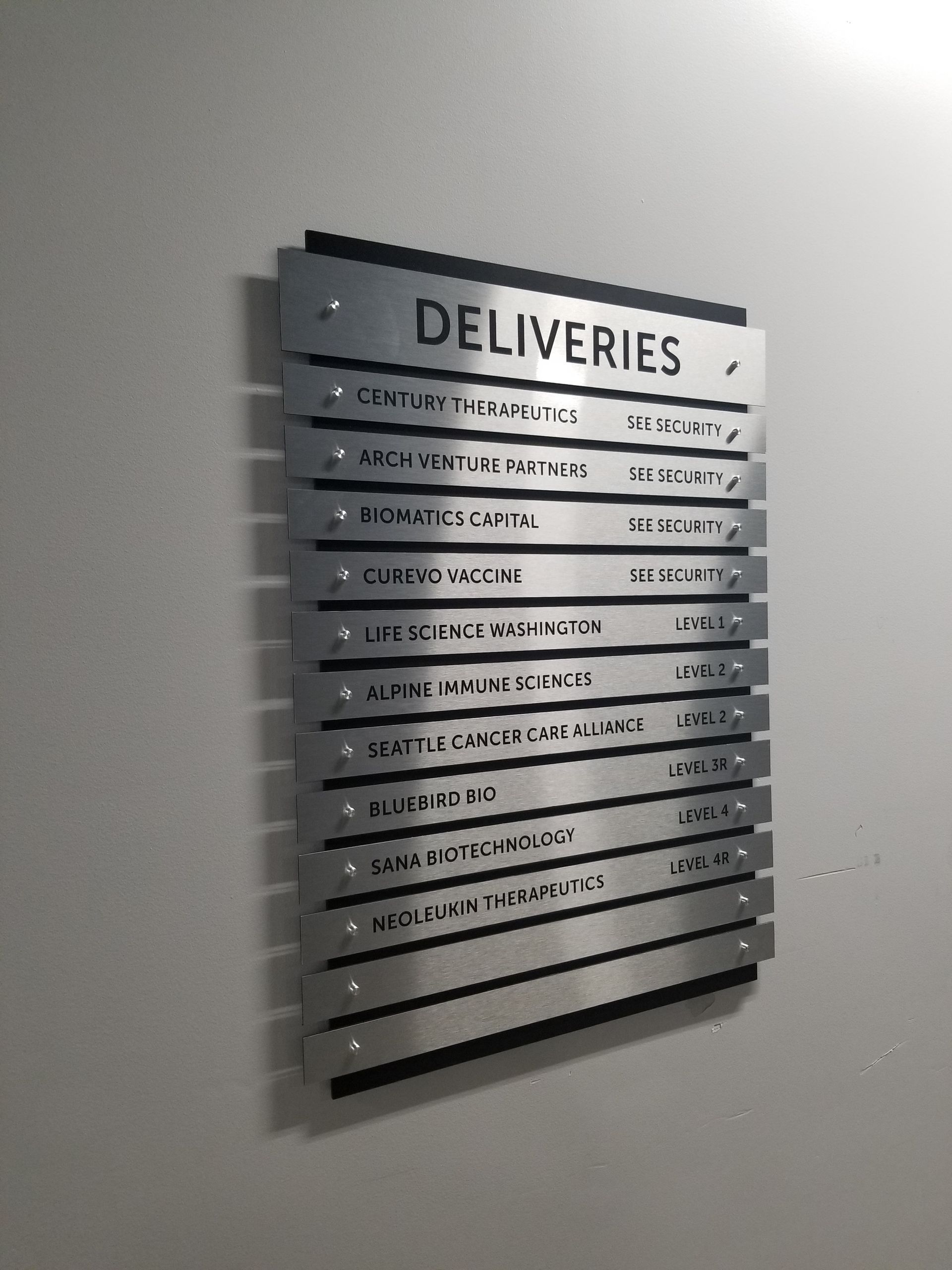 Silver sign with company names listed on a white wall