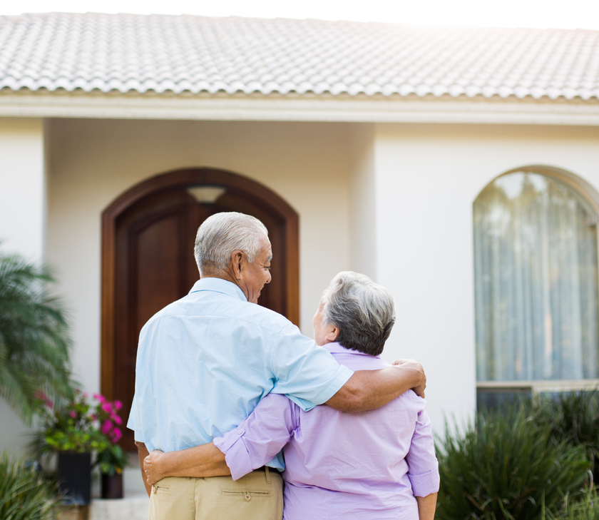 Senior couple standing outside their home looking at newly replaced roof.