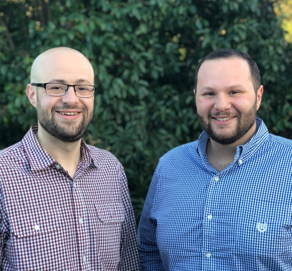 Two men are standing next to each other and smiling for the camera.