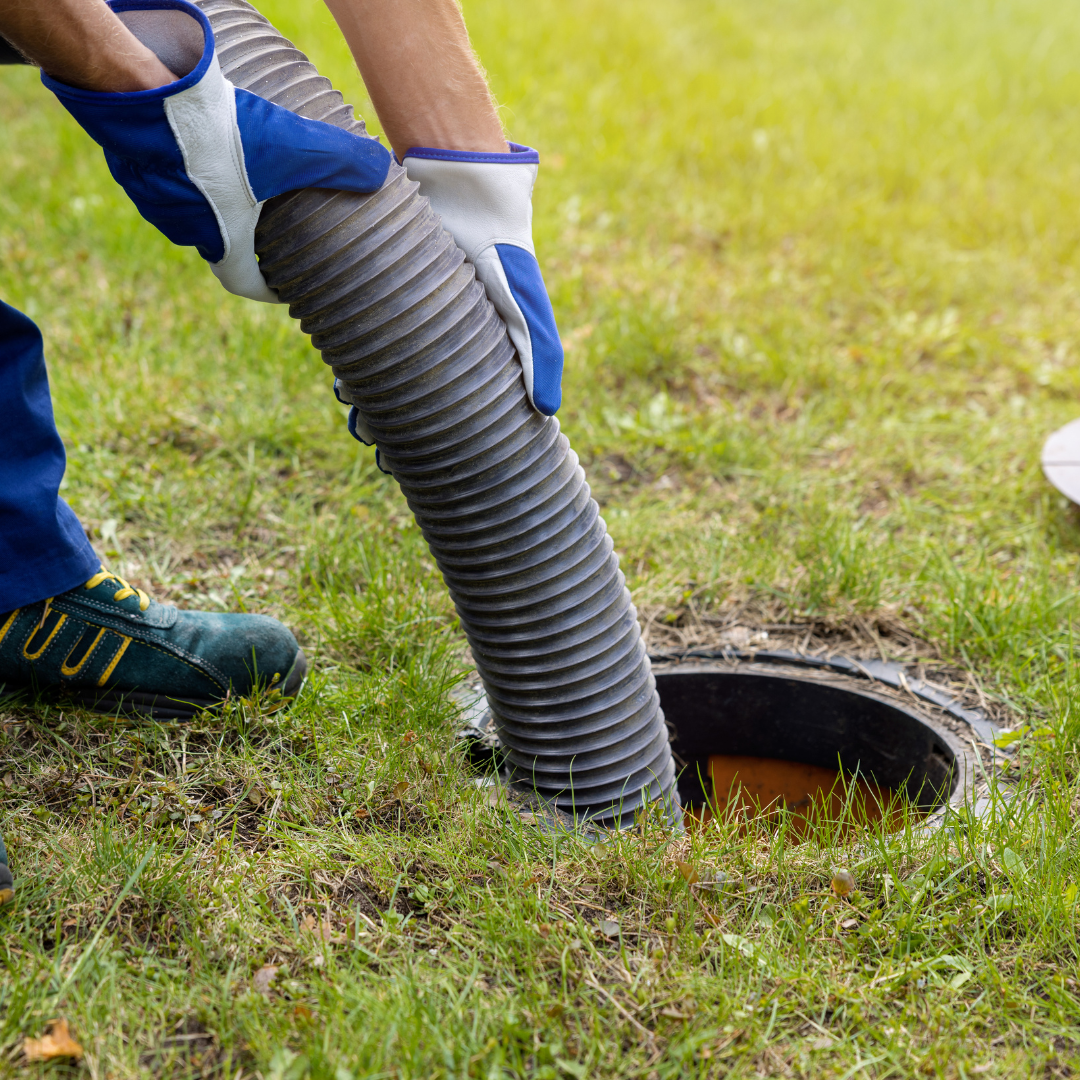 A person is pumping a hose into a hole in the ground.