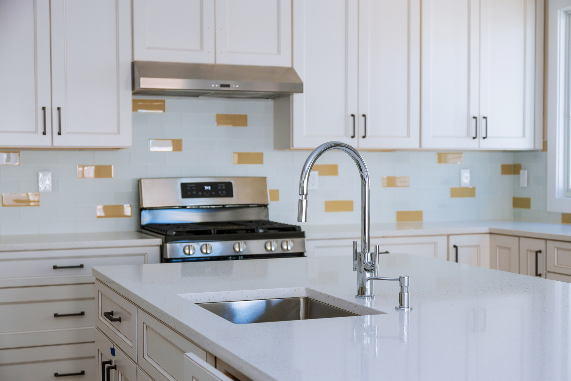 A kitchen with white cabinets , stainless steel appliances , a sink and a stove.