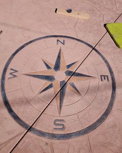 Elegant gray house with a large paved driveway and well-manicured landscaping on a sunny day.