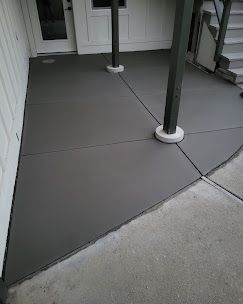 House with brick facade, two-car garage, and long, curved concrete driveway edged by green grass.