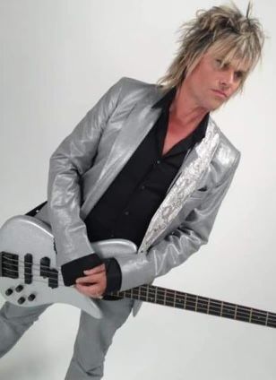 A man in a silver suit is holding a white guitar