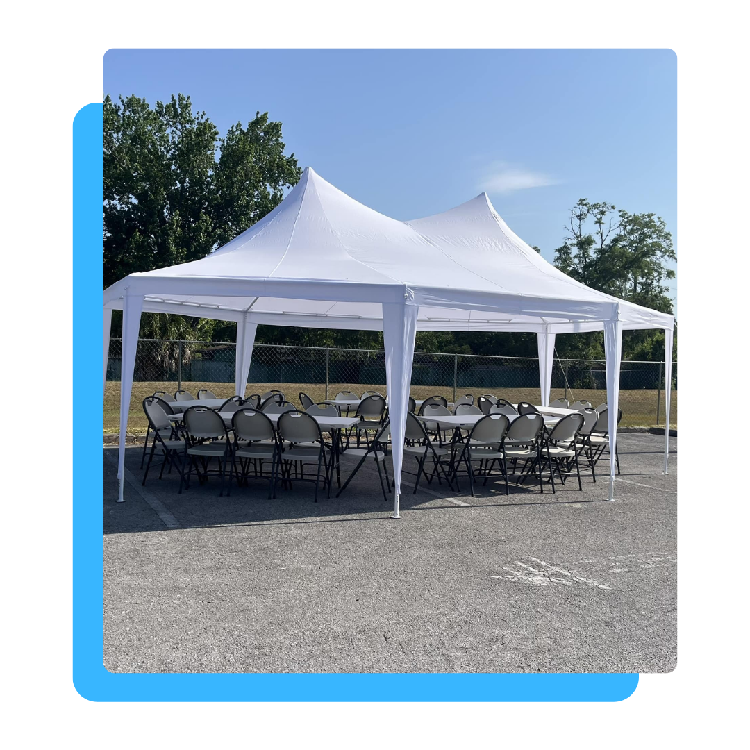 A white tent with tables and chairs underneath it in a parking lot.