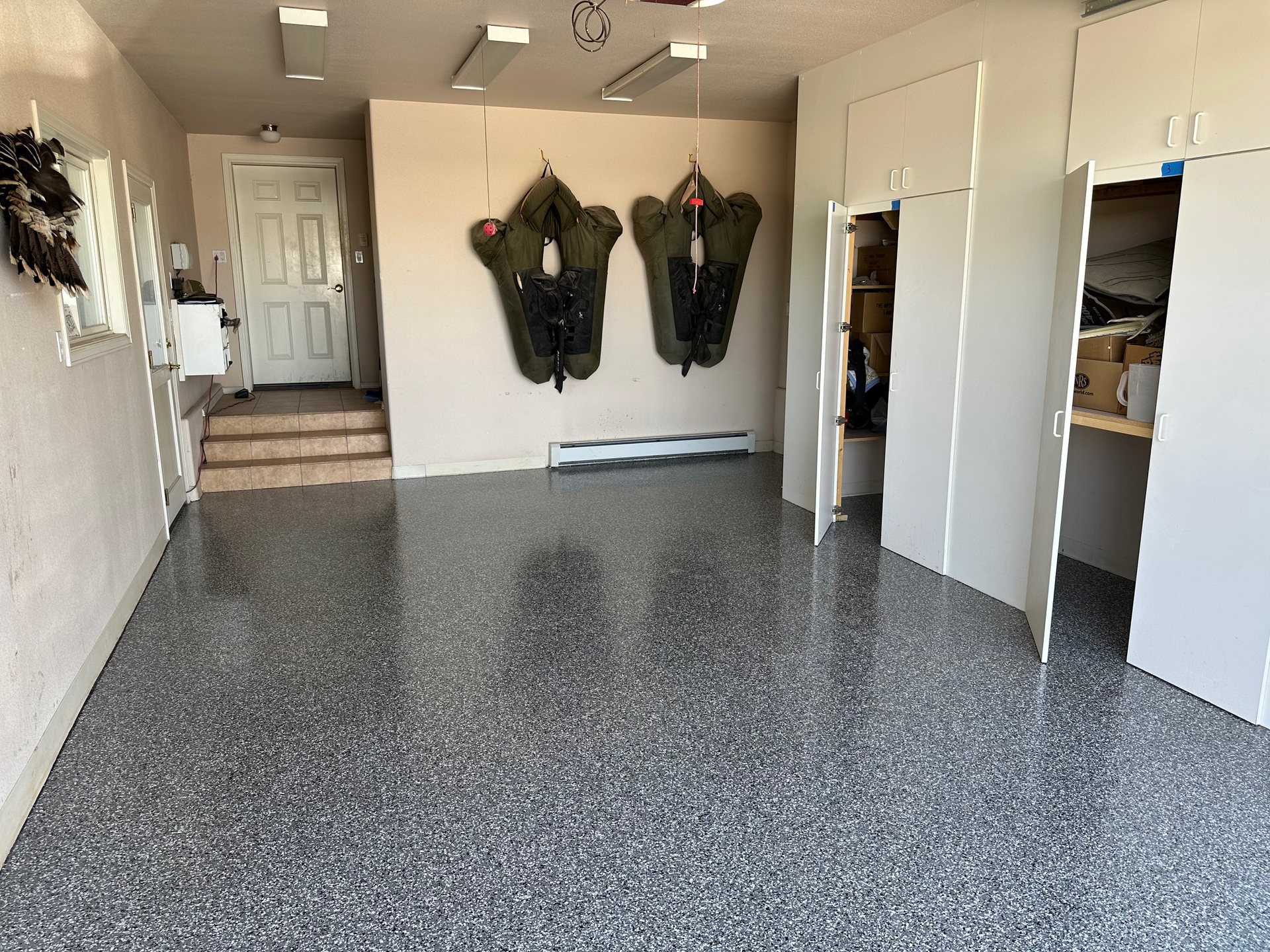 A garage with a gray floor and two jackets hanging on the wall