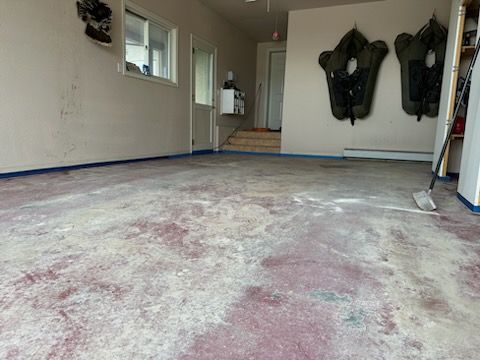 A dirty floor in a garage with a shovel on it.