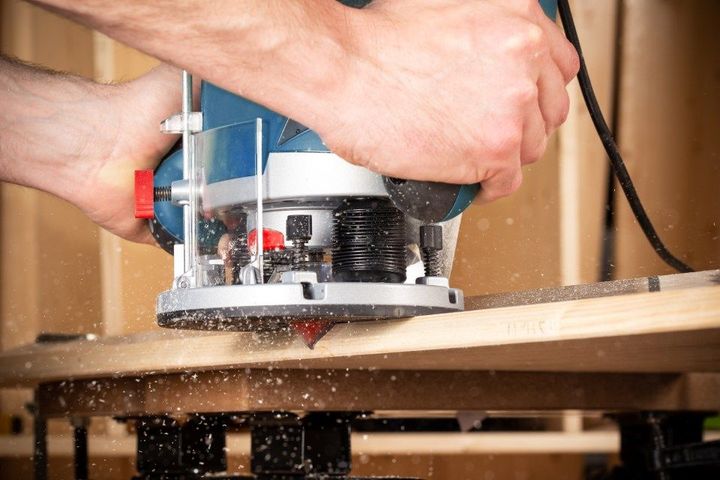 A person is using a router to cut a piece of wood.