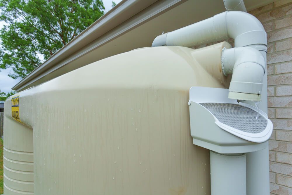 Tan Water Tank with White Pipes Collecting Rainwater from A Gutter — All-Clear Gutter Guard NQ in Tolga, QLD