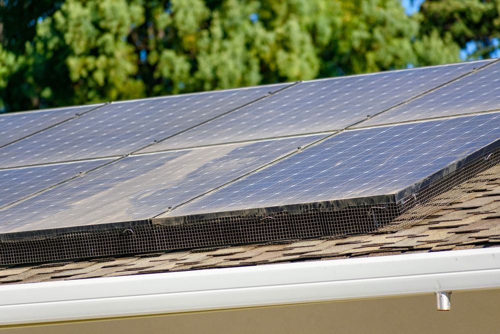 Solar panels installed on a brown shingled roof, showing some dust — All-Clear Gutter Guard NQ in Cairns City, QLD