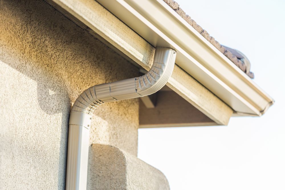 White Gutter and Downspout on A Tan Stucco Building — All-Clear Gutter Guard NQ in Walkamin, QLD